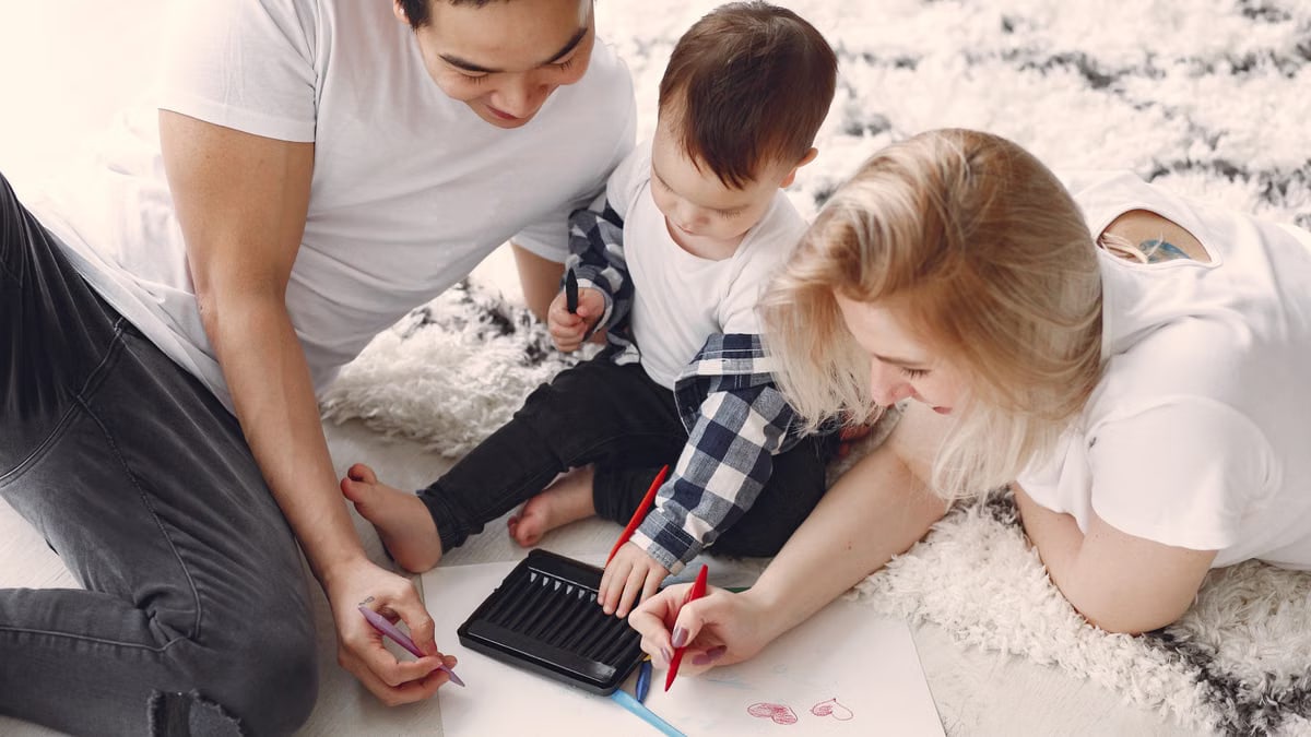 Parents and child enjoying drawing together on the floor, creating memories.